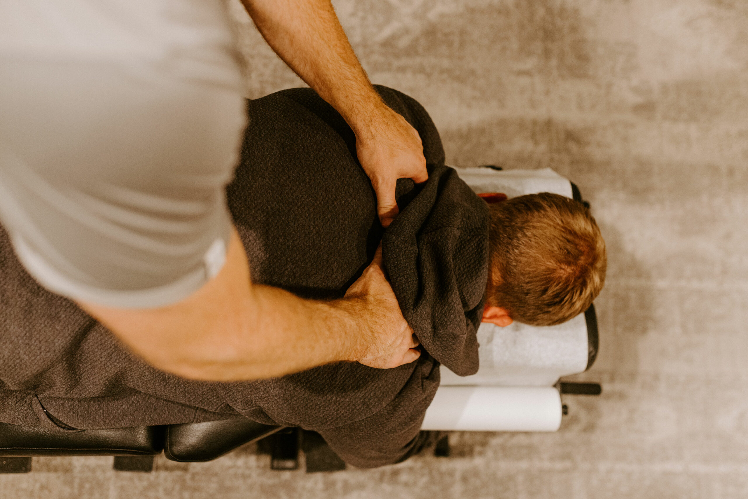 panoramic shot of chiropractor massaging neck of man on grey